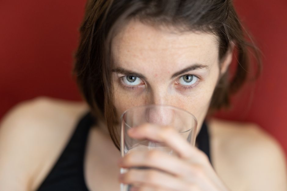 A young woman drinking water, offering a close-up view with a soft focus on her expression