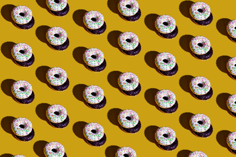 Vibrant pattern of donuts with sprinkles on a yellow background.