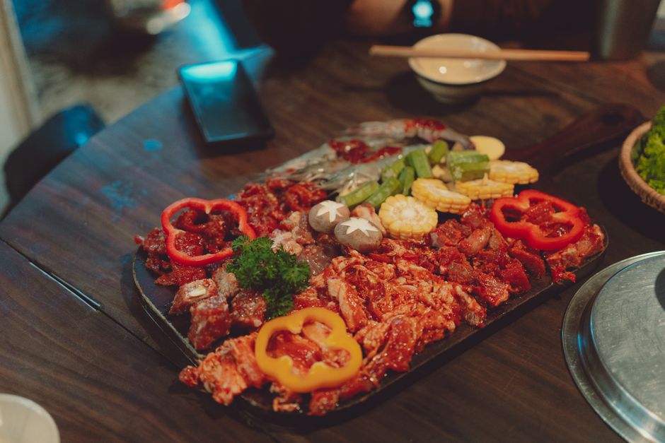 A colorful close-up of a meat and vegetable platter ready for grilling, captured in a Vietnamese restaurant.