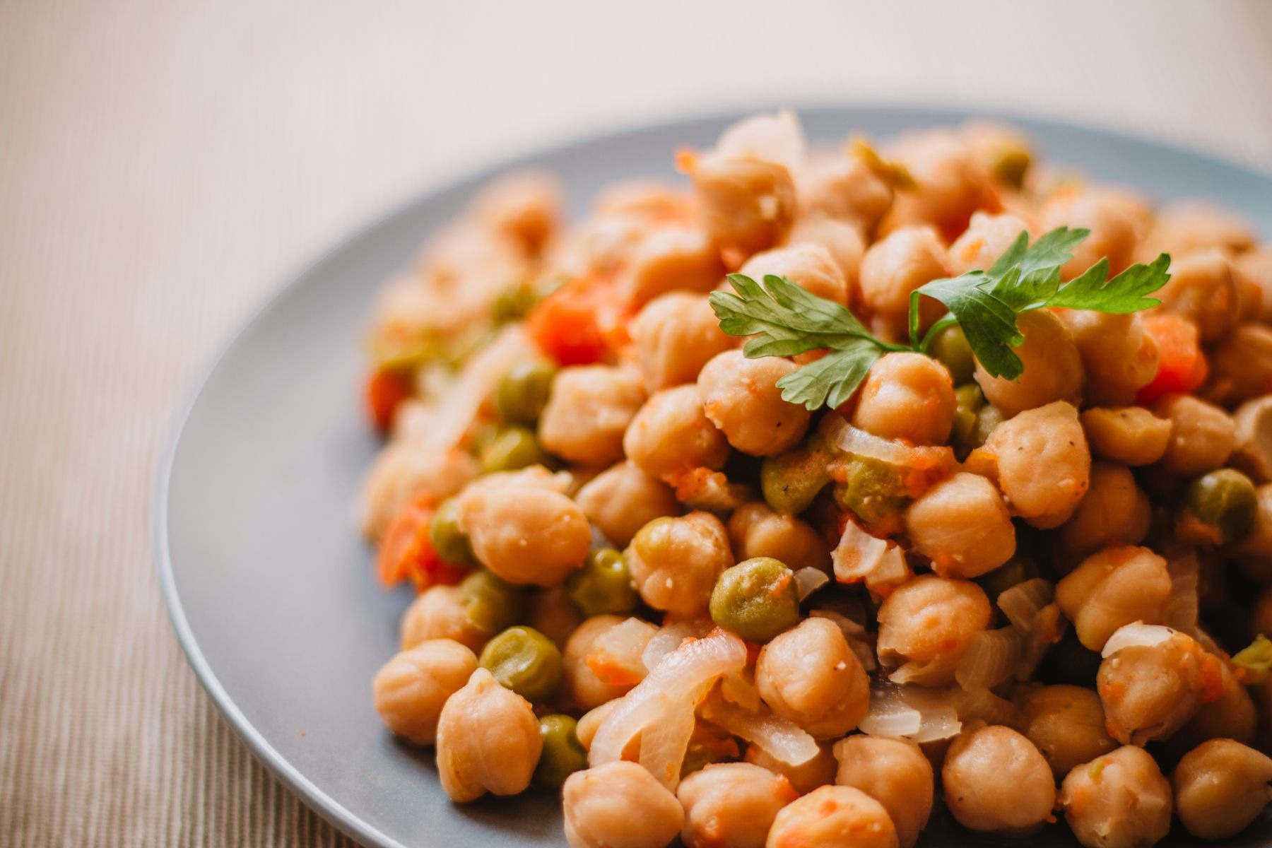 Chickpeas with peas, corn and diced vegetables on a plate; cucumber is not evident.