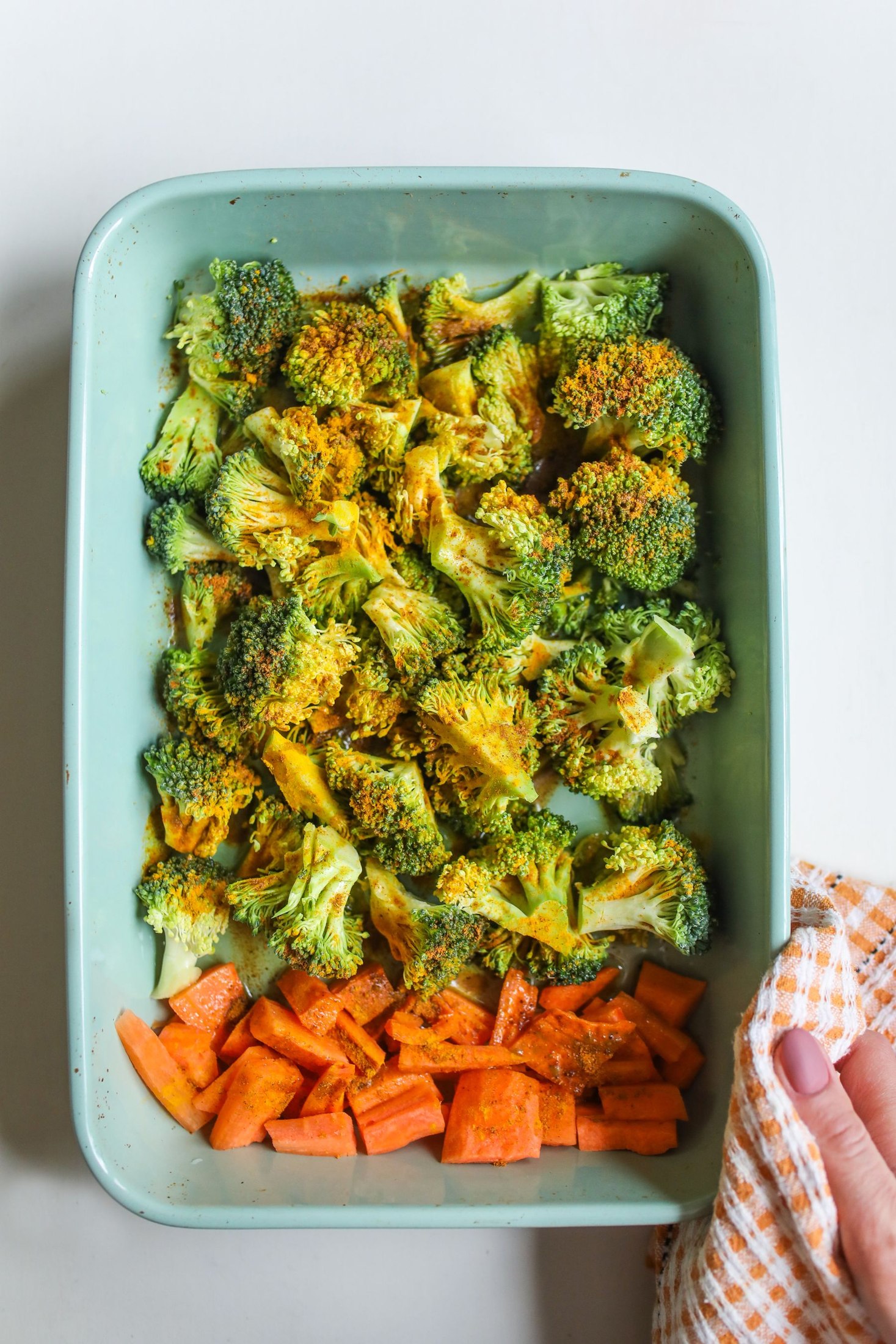 Broccoli florets and sliced carrots on a roasting tray.