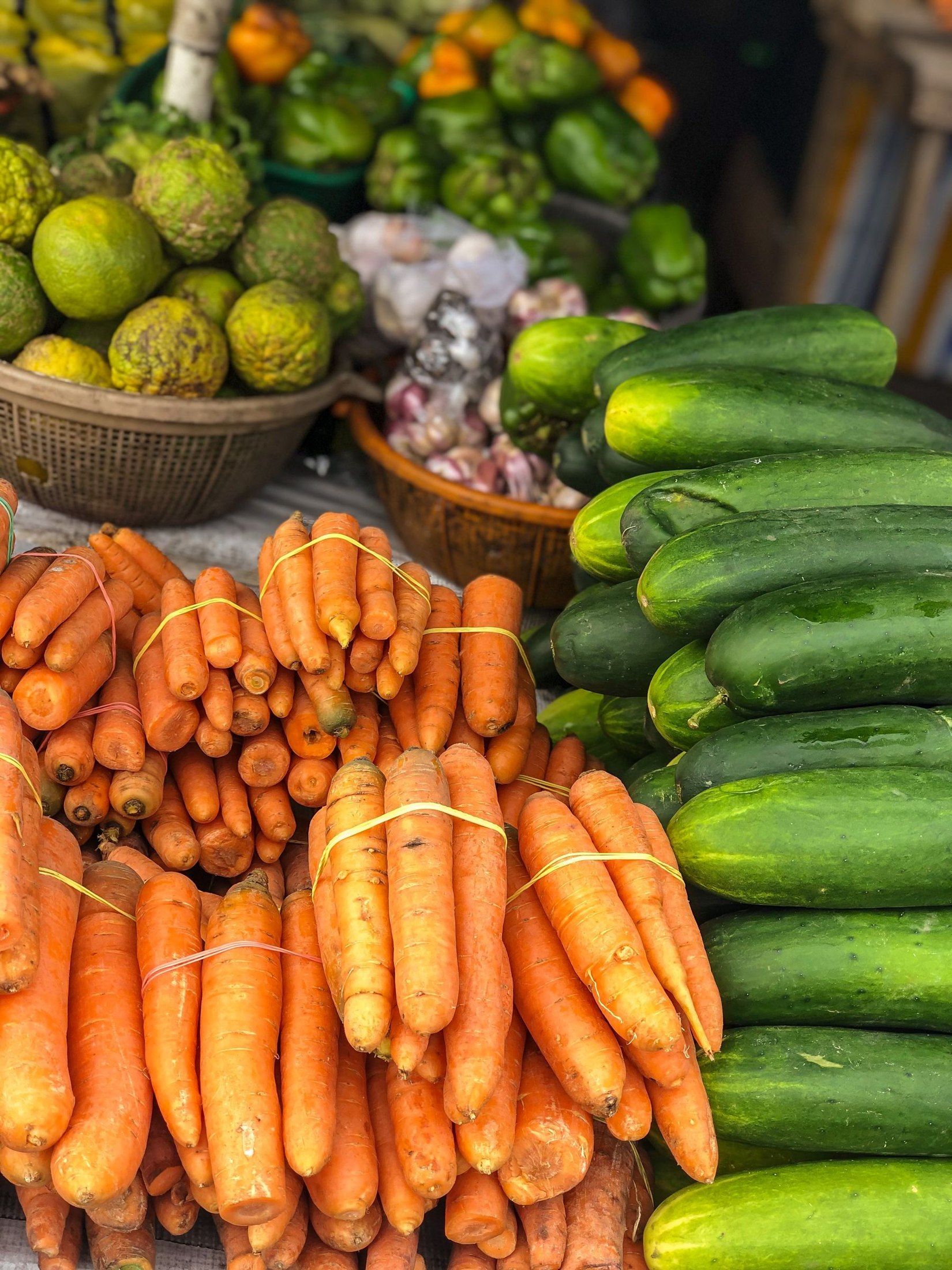 Fresh vegetables including carrots, cucumbers and garlic at an outdoor market.