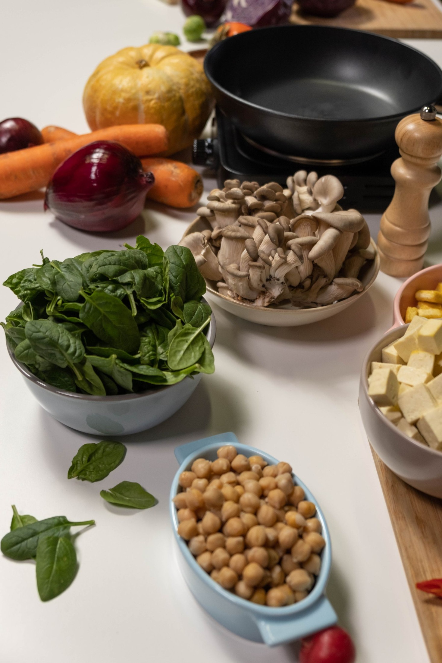 Raw spinach, chickpeas and mushrooms near cookware.