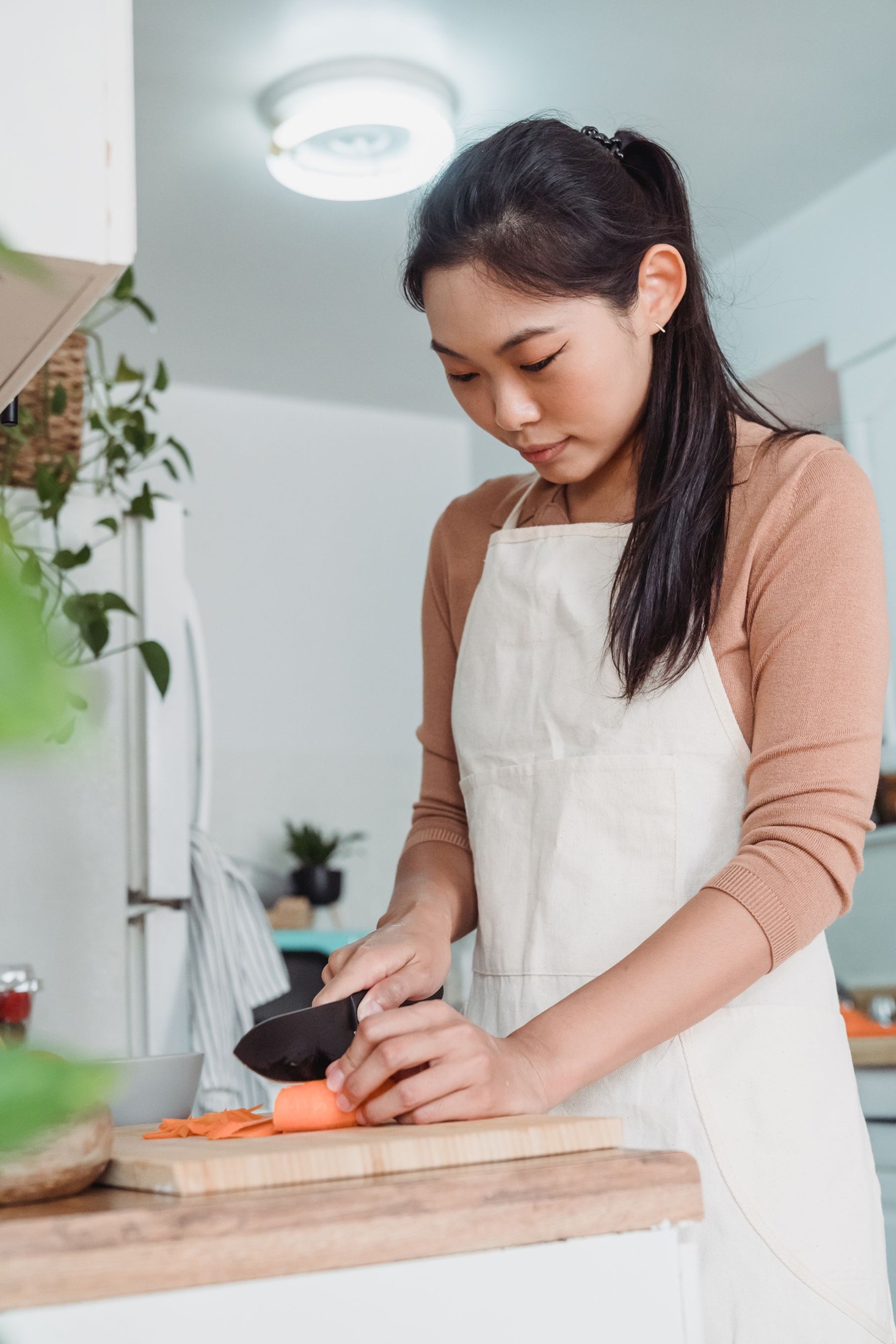 Woman slicing carrots on a kitchen chopping board.